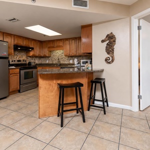 Warm wood cabinetry complements the granite counter in this inviting kitchen area, featuring a breakfast bar with seating