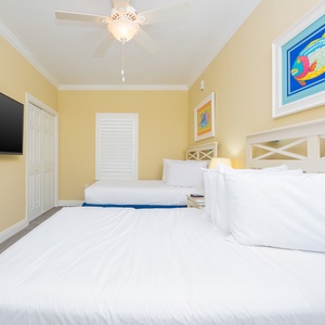 Cheerful artwork complements the cozy guest bedroom featuring two double beds and a wall-mounted TV for entertainment