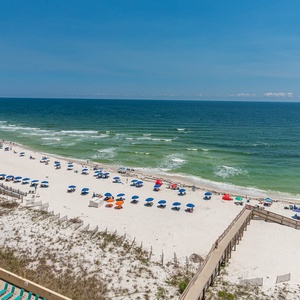 Vibrant beach umbrellas dot the sandy shore, inviting guests to relax by the sparkling turquoise waters