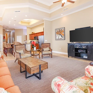 This inviting living area features an orange sofa, tropical accents, and a large TV, perfect for relaxation and entertainment