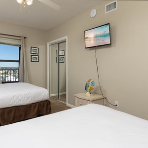 Inviting guest bedroom with two queen beds, a TV for entertainment, and a window offering a lovely view