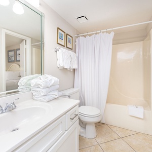 Bright bathroom featuring a spacious vanity, ample towels, and a relaxing shower area for your comfort