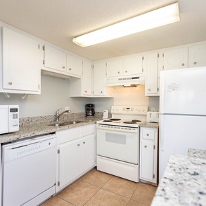 This kitchen features white cabinetry, granite countertops, and essential appliances for a delightful cooking experience