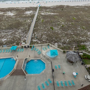 Vibrant pool area features a kiddie pool, lounge chairs, and a path leading to the beach, creating a relaxing vacation vibe