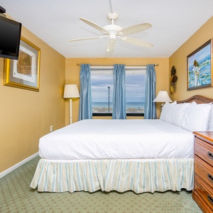 This bedroom features a comfortable bed, a TV, and lovely views through blue curtains, perfect for relaxation