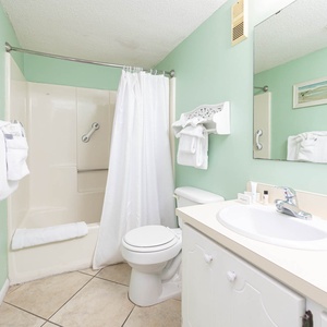 Master bath featuring a tub/shower combo, fresh towels, and a soothing mint green color scheme