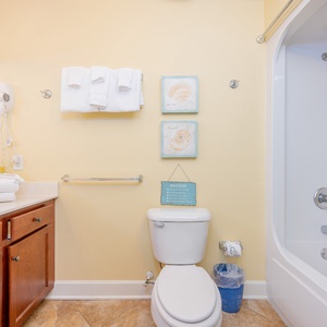 Refreshing guest bathroom featuring a tub/shower combo, fresh towels, and beach-themed decor for a relaxing stay