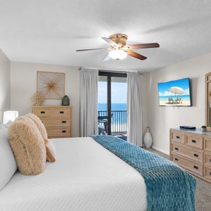 Bright and airy master bedroom featuring a king bed, dresser, modern decor, and a balcony with a view of the gulf