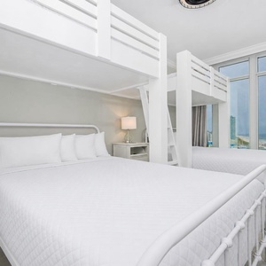 Charming bunk room with two lofted twin beds above two cozy queen beds below and stunning beach views