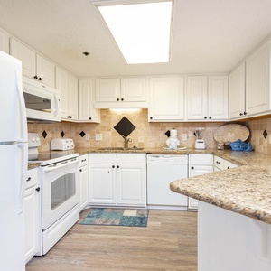 White cabinetry complements the granite countertops in this fully-equipped kitchen, featuring a convenient breakfast bar