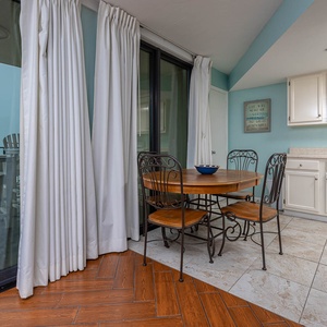This inviting dining area features a round wooden table, stylish chairs, and a view of the balcony, perfect for relaxation