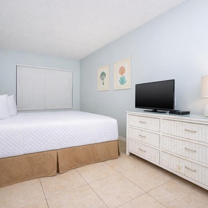 This bedroom features a comfortable bed, stylish decor, and a TV, perfect for relaxing after a day at the beach