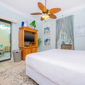 The master suite features a king bed, wooden dresser, and a view into a cozy patio area through sliding glass doors