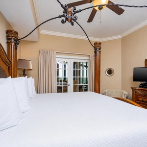 The master bedroom features a plush king bed, a TV for entertainment, and access to a serene outdoor view