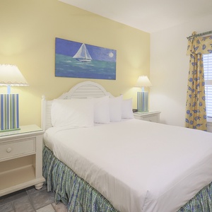 Cozy guest bedroom featuring a queen bed, cheerful yellow walls, and nautical decor with a vibrant painting above the bed