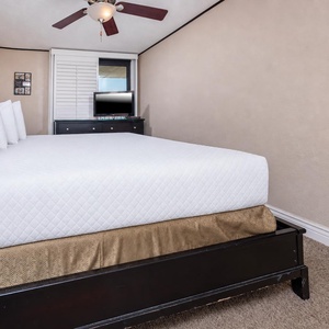 The master bedroom features a king bed, a TV for entertainment, and soft lighting, creating a restful retreat