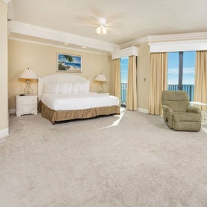 Spacious master suite bedroom, featuring a king bed, cozy seating, and beachfront balcony access