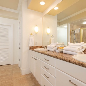 This bathroom features a double vanity with granite countertops, fresh towels, and a spacious shower for a relaxing retreat