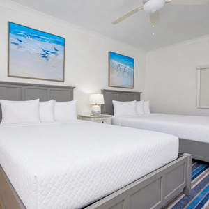 Experience restful nights in this inviting guest bedroom with two plush queen beds, coastal artwork, and soothing colors