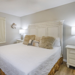 Inviting guest room featuring a plush king bed with decorative pillows, warm lighting, and soft neutral tones for relaxation