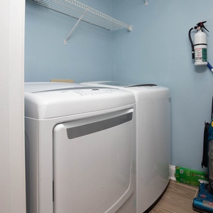 A laundry area features a washer and dryer, complemented by a wall-mounted shelf and a vacuum cleaner for convenience