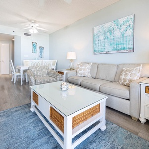 Living space features a light gray sofa, accent chair, and a glass-top coffee table, creating a welcoming atmosphere