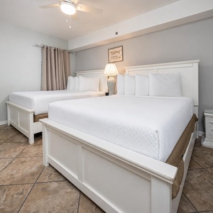 Guest bedroom featuring two double beds, soft linens, and beach-inspired artwork for a relaxing retreat