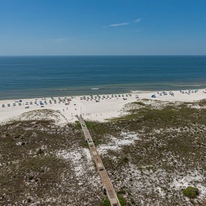 View of the beach and colorful umbrellas, leading to the calm gulf waters under a clear blue sky