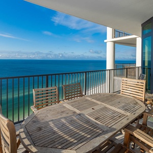 Enjoy dining on the spacious balcony with beachfront views and comfortable wooden furniture for relaxation