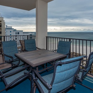 Spacious balcony features a table and chairs, offering a relaxing spot to enjoy views of the tranquil beach and gulf waters