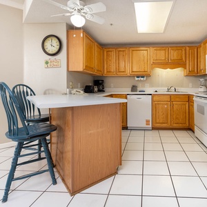 Prepare meals in the spacious kitchen featuring ample counter space, wooden cabinets, and seating at the breakfast bar