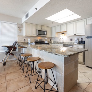 The kitchen features stainless appliances, granite countertops, and a breakfast bar with stools and an infant feeding chair