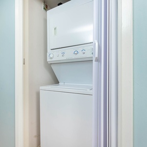 Stacked washer and dryer set in a laundry nook with light blue walls, providing convenient in-unit laundry access