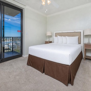 Queen bed in the guest suite sets a restful scene beside glass doors revealing coastal community views