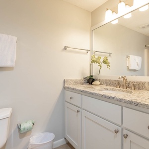 Bright and airy guest bathroom featuring a spacious vanity with elegant fixtures, fresh towels, and a colorful shower curtain