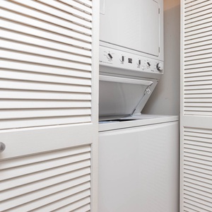 This laundry area features a stacked washer and dryer behind stylish louvered doors for your convenience