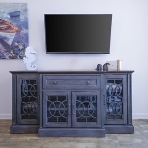 A stylish media console with decorative accents and a flat-screen TV complements the vibrant coastal artwork on the wall
