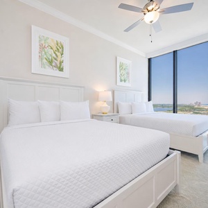 Relax in this guest bedroom featuring two queen beds and stunning coastal views