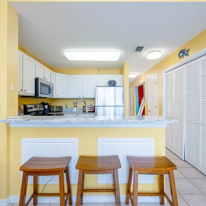 This cozy kitchen features bright yellow walls, stainless appliances, and a bar area with stylish seating for casual dining