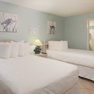 Cheerful guest bedroom with two double beds, beach decor, and soft lighting for a restful atmosphere