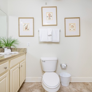 Refreshing guest bathroom featuring elegant shell artwork, a spacious granite countertop, and a clean tub/shower combo