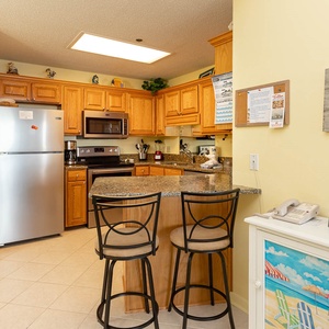 Brightly colored kitchen features wooden cabinetry, stainless appliances, and a breakfast bar for convenient entertaining