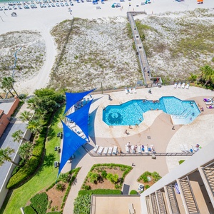 Enjoy the inviting pool area with shaded seating, surrounded by lush landscaping and just steps from the beach access