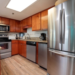The kitchen features rich wood cabinetry, granite countertops, and stainless appliances, creating a warm and functional space