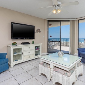 Living area featuring a TV, comfortable blue chairs, sofa with queen sleeper, and a view of the beach from the balcony