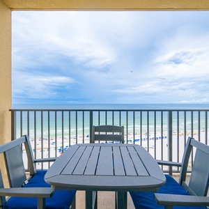 Balcony offering a direct view of the beach and vibrant blue waters beyond, showcasing boats just off the coast