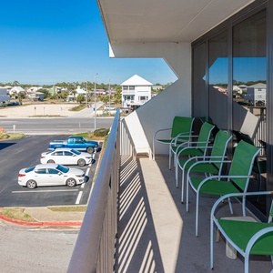Enjoy a relaxing moment on the balcony with green chairs, overlooking the charming neighborhood and nearby parking