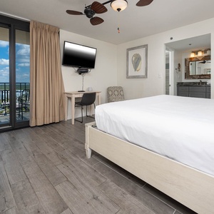 Relaxing master bedroom featuring a comfortable king bed, a flat-screen TV, and a balcony with a scenic view