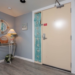 This welcoming entryway features a stylish mirror, soft lighting, and beach-themed decor, perfect for a relaxing getaway
