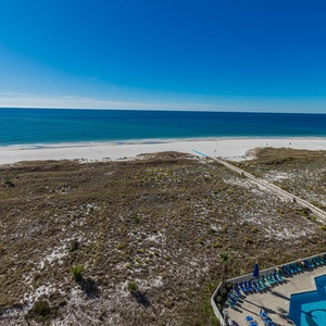 Stunning view of the tranquil beach, with a pool area featuring lounge chairs below